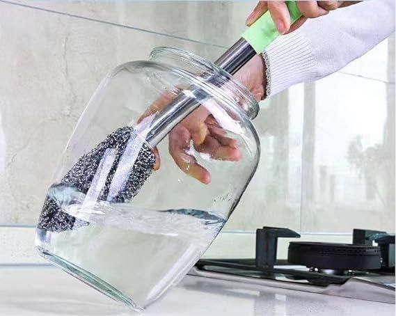 Hand using a bottle jar scrubber for effective cleaning of large glass jars in the kitchen