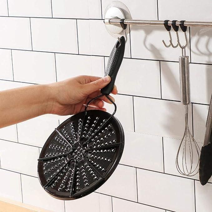Hand holding a gas and electric stove diffuser with a round design hanging on a kitchen rack
